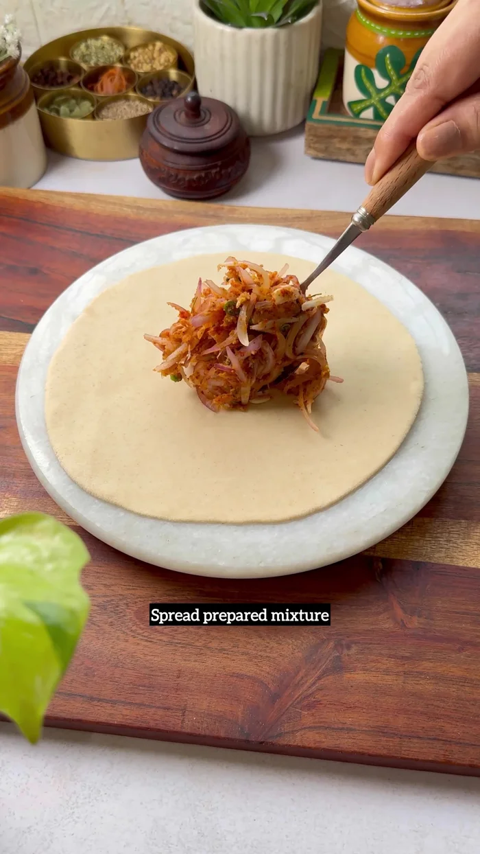 Roll out roti dough. Spread the onion mixture. Make a cut, fold, and press.