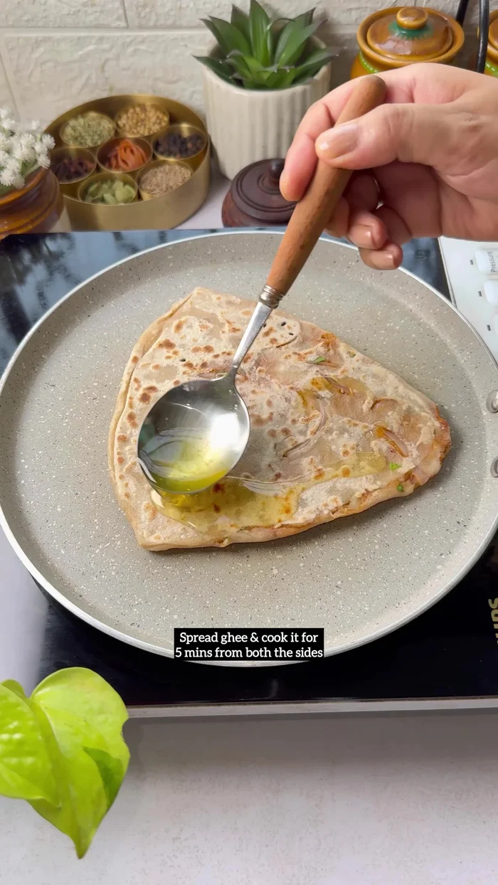 Add nigella seeds and coriander leaves, shape into a paratha, and cook for 5 minutes per side with ghee.