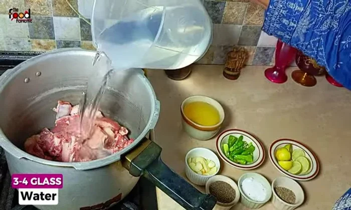 Add 3-4 glasses of water to the pressure cooker, ensuring the meat is fully submerged.