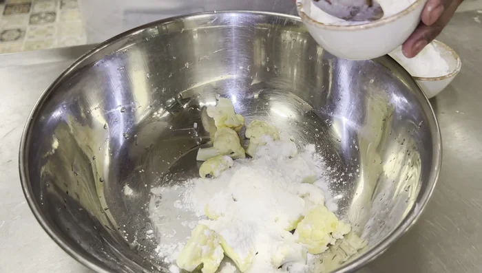 In a bowl, combine the cauliflower, cornflour (and rice flour if using), salt, aromat mix, chilli paste, green coriander, and enough water to make a batter that sticks well to the cauliflower.