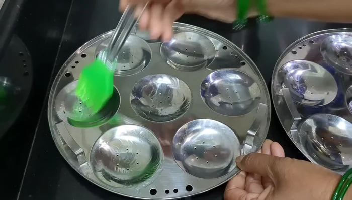 Lightly grease idli plates with oil using a silicon brush.