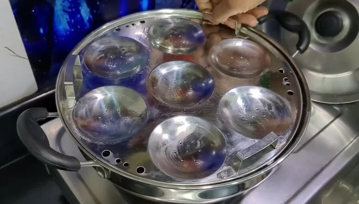 Fill the greased idli molds halfway with the batter.