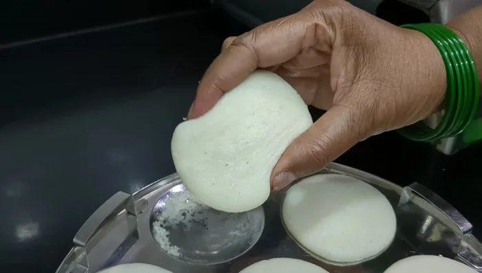 Once cooked, carefully remove the idli from the plates.