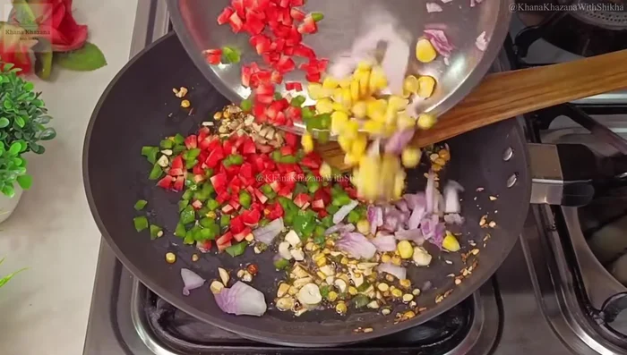 Add finely chopped onion, capsicum, carrot, and sweet corn to the tempering. Sauté for 2 minutes on high flame until slightly softened, being careful not to overcook.
