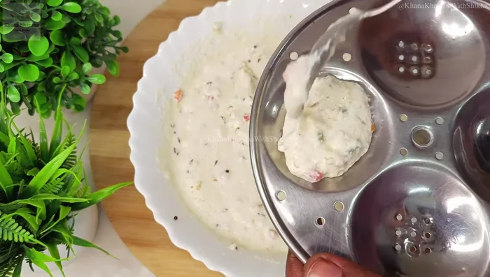 Pour the batter into the greased idli molds, not overfilling them.