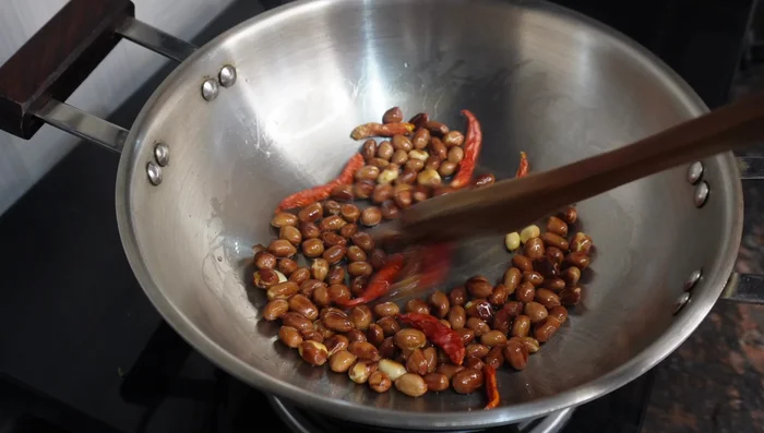 Add red chili to the peanuts and roast until slightly softened.