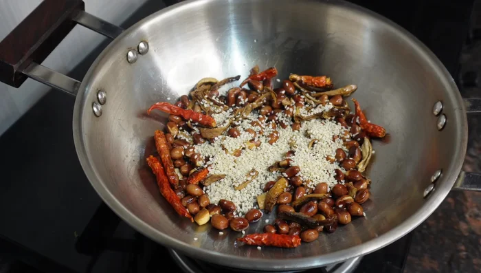 Add dry mango powder, white sesame seeds, coriander seeds, cumin seeds, and asafoetida. Roast these until fragrant.