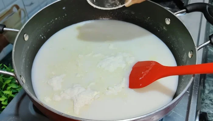 Add milk powder and crushed cardamom to the boiling milk. Stir well.