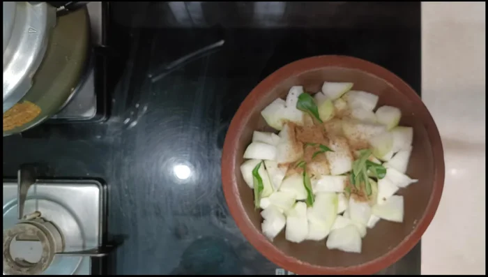 Add the ash gourd cubes to a mud pot or pan. Add curry leaves, jaggery, salt, turmeric powder, tamarind juice, and water. Mix and cook until the pumpkin is soft but firm. (43.52)