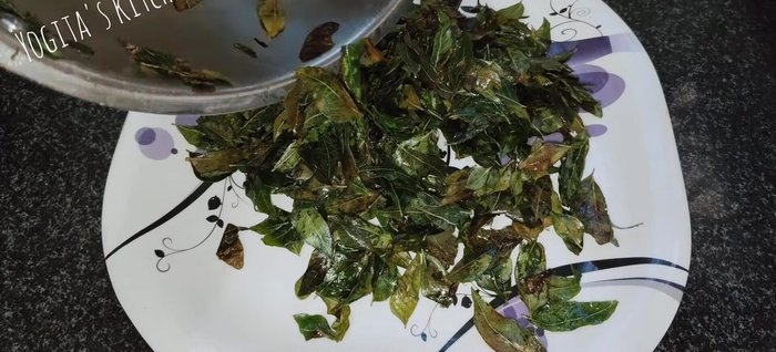 Spread the roasted curry leaves on a plate to cool down.