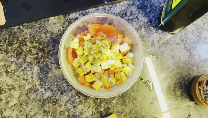 Season the tomato and paneer mixture with mixed herbs, salt, apple cider vinegar, and olive oil.