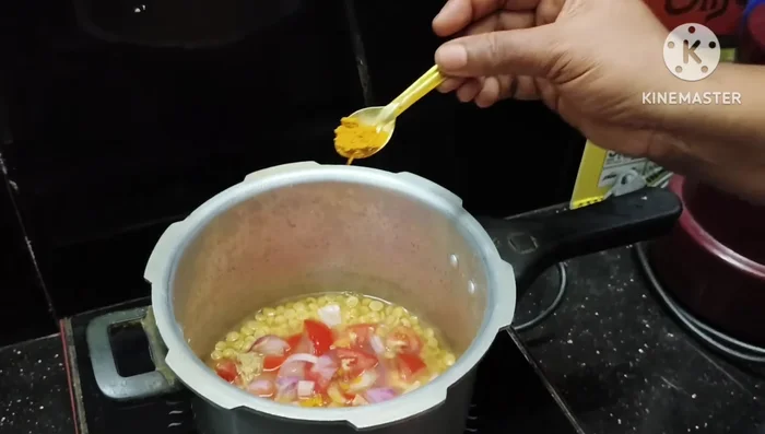Add the chopped tomatoes and onions to the half-cooked peanuts, along with half a teaspoon of turmeric powder. Cook well.