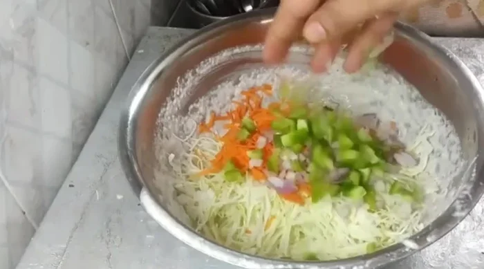 Prepare the vegetable mixture: finely chop carrots, onion, capsicum, and green coriander. Add asafoetida, coriander powder, turmeric powder, and chili powder. Mix well.