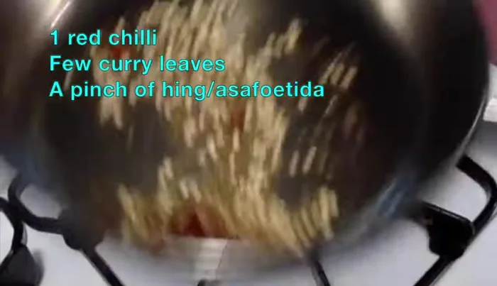 Add a fried red chili, curry leaves, and hing to the tempering. Fry briefly and switch off the flame.