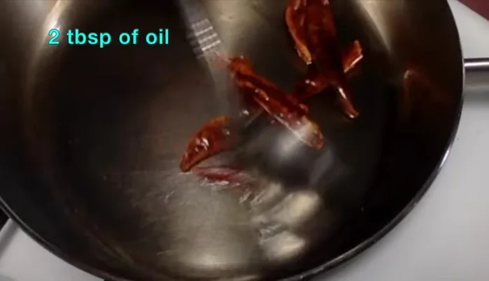 Heat oil in a pan. Fry red and green chilies until they turn brown. Transfer to a plate to cool.