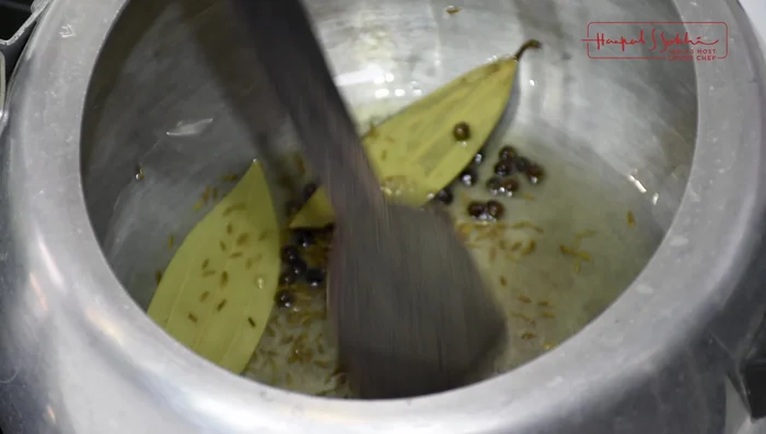 Add cashew nuts, almonds, raisins, and black currants to the pressure cooker. Lightly fry until fragrant.