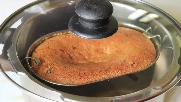 Place the baking tray/tin in the pan. Cover and cook for 25-30 minutes on low flame, checking occasionally with a toothpick. The cake is ready when the toothpick comes out clean.