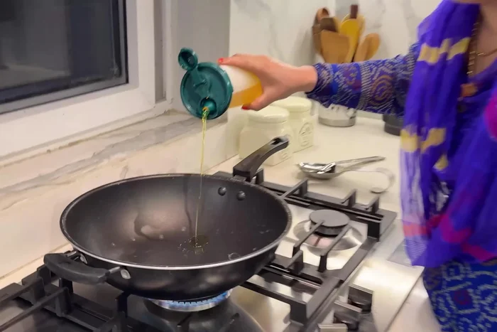 Heat oil in a kadai. Add chopped onions and fry until softened. Add a pinch of salt to speed up the softening process.