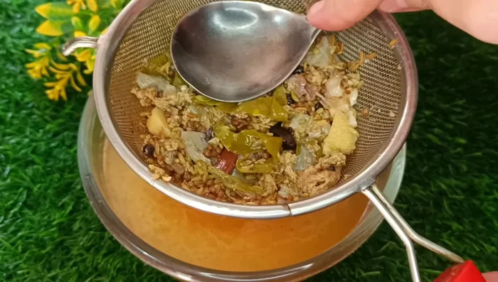 Press the spices in the sieve to extract all the juice. Squeeze the garlic to extract its pulp and add it to the yakhni.