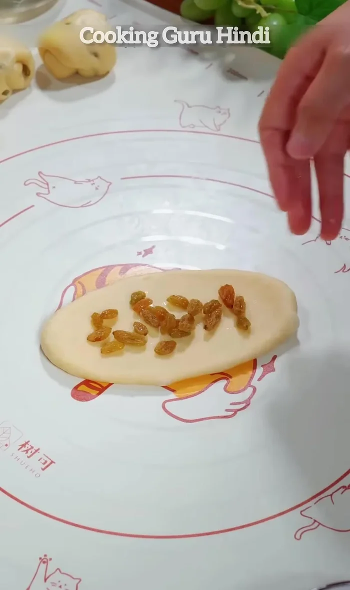 Place a layer of raisins on it and roll from one edge. Roll out again and then roll again.