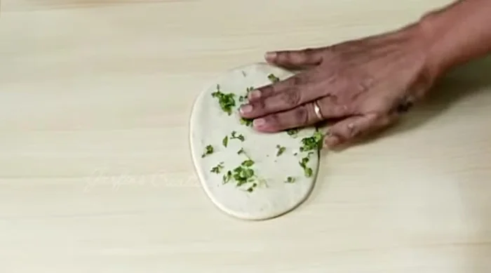Sprinkle fresh coriander, garlic (if not added earlier), nigella seeds, or sesame seeds on top of each rolled naan. Roll again to incorporate the toppings.