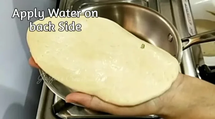 Place the naan on the hot pan, press lightly, and cook until small bubbles appear. Flip and cook until brown spots form.