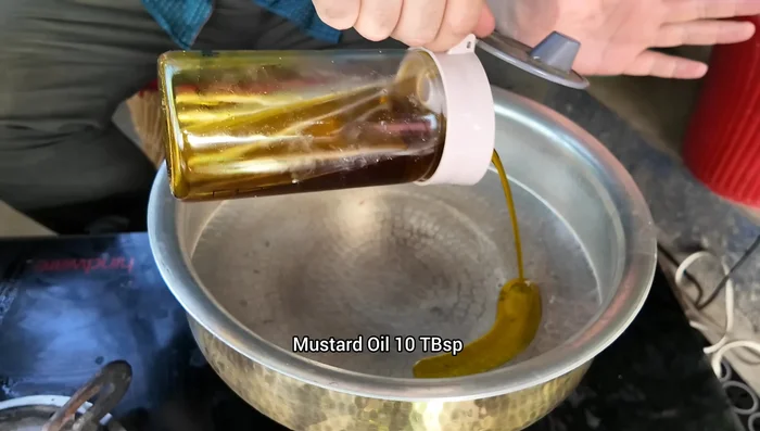 Heat mustard oil in a pot, add garlic cloves, and saute until fragrant.