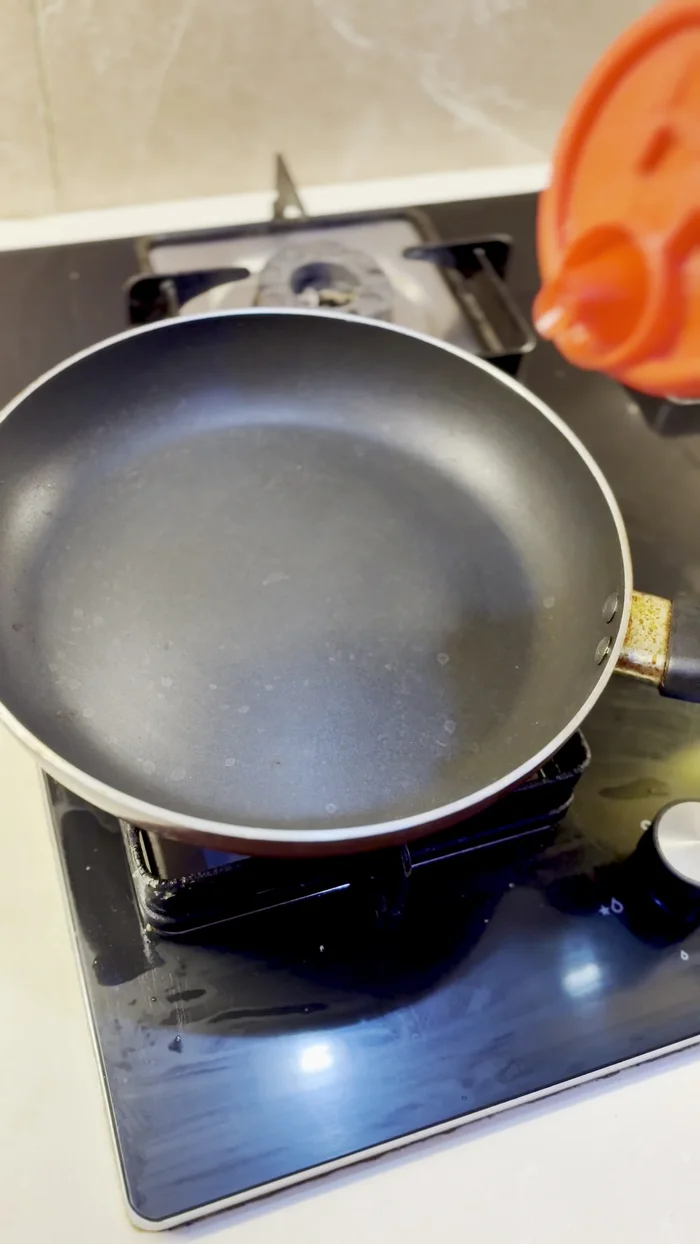 Light the stove, place a pan on it, and add 2 tablespoons of oil. Once the oil is slightly hot, add the urad dal one by one.