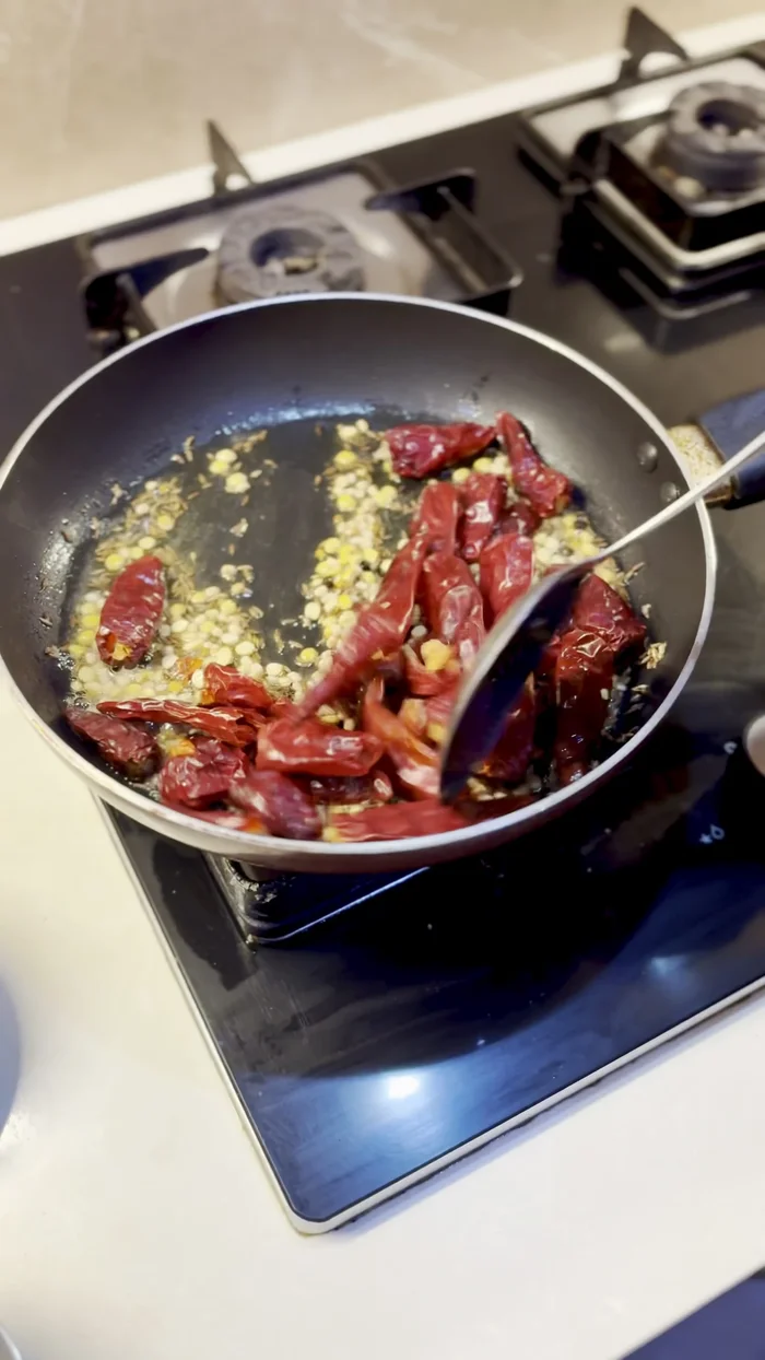 Add dried chilies and fry for two minutes. Then add garlic and tamarind and fry for a few seconds, stirring in between.