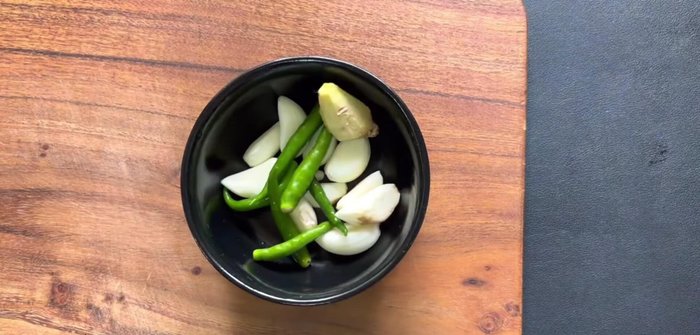 Grind garlic, green chilies, and ginger into a paste.
