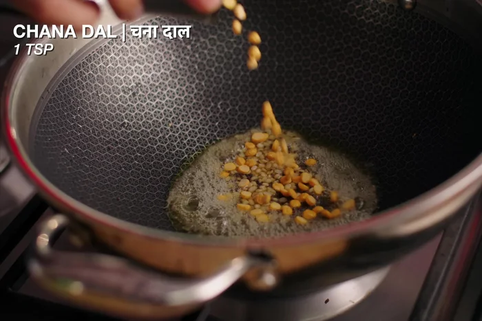 Temper the spices: Add mustard seeds to the pan. Once they crackle, add urad dal and chana dal. Fry until lightly colored.