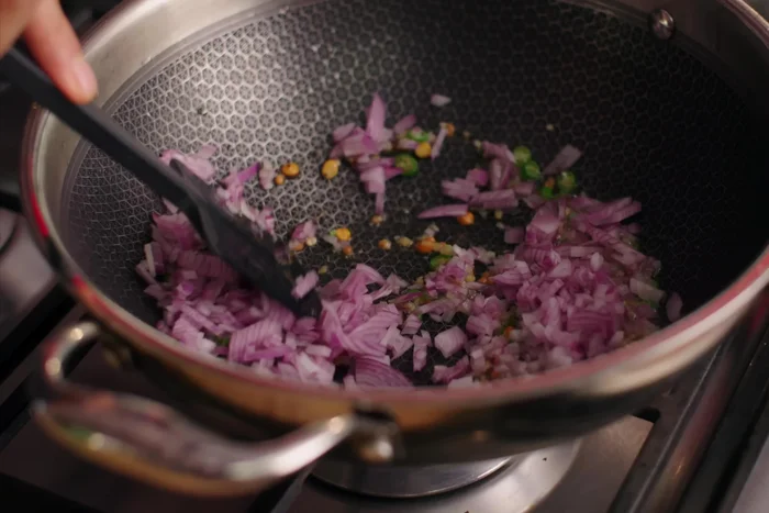 Sauté aromatics and vegetables: Add chopped ginger, green chilies, and onion. Sauté until onions become translucent. Add curry leaves and other chopped vegetables, stir and cook for 2-3 minutes.