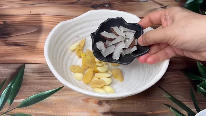 Grind ginger, garlic, coconut, almonds, sesame seeds, green chilies, cloves, cardamoms, cinnamon, black pepper, and coriander leaves into a fine paste.