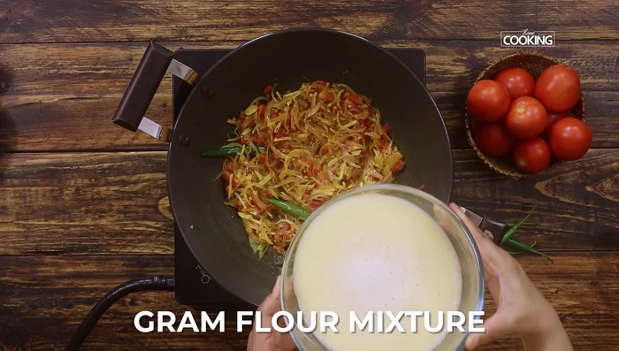 Pour the gram flour mixture into the karai. Add curry leaves and mix well.