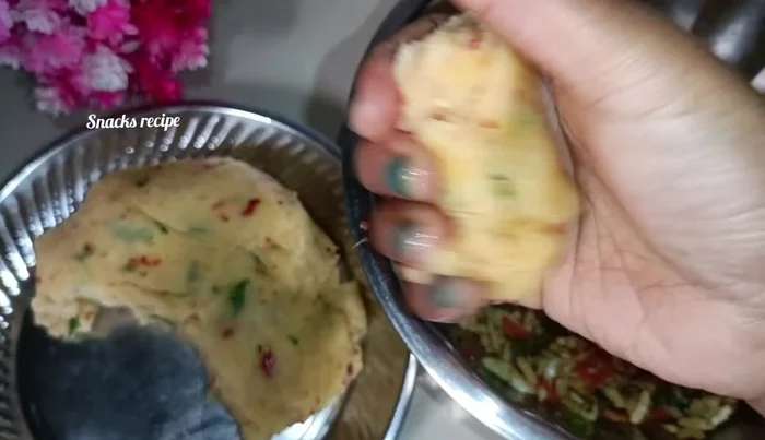 Grease your hands. Take a small portion of the semolina dough, make a ball, flatten it slightly, and add the puffed rice stuffing.