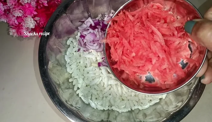 Add finely chopped onion, grated carrot, finely chopped cabbage, green chili, and ginger to the puffed rice.