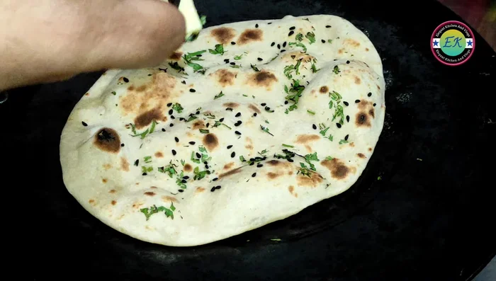 Remove the naan from the tawa and immediately apply butter while still hot.