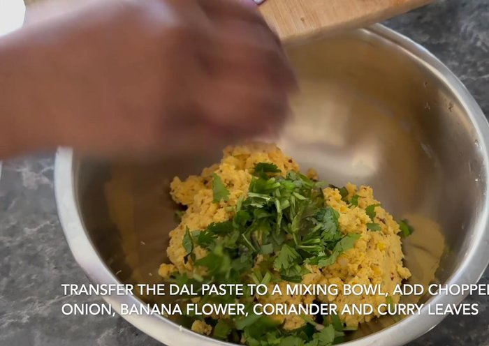 Transfer the paste to a mixing bowl. Add chopped banana flower, onion, coriander leaves, and curry leaves.