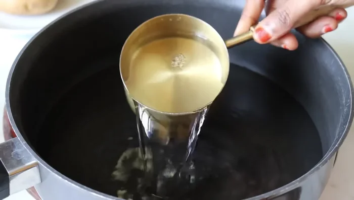 In a wide pan, add 4 cups of water, the drained and squeezed grated potatoes, and 0.5 teaspoon of salt. Bring to a boil on high heat, stirring occasionally.