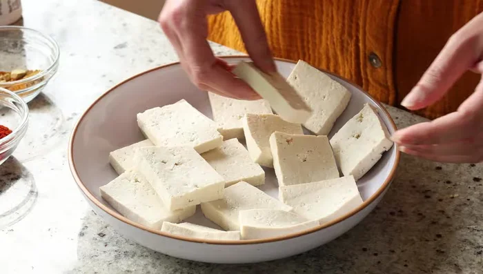 Toss tofu slices in a mixture of cornstarch, Kashmiri chili powder, garlic powder, and salt.