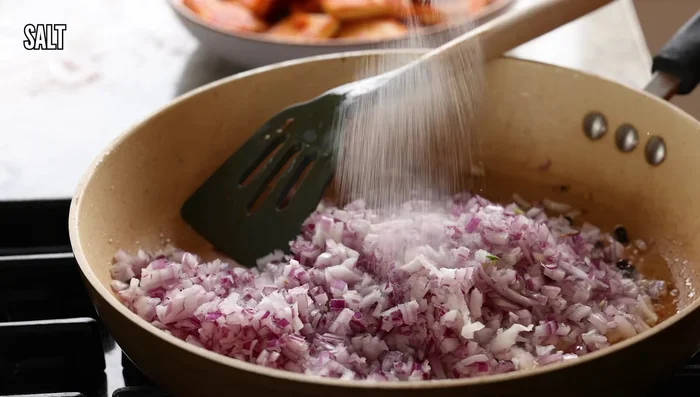 In the same skillet, add fennel seeds and whole peppercorns. Add chopped onion and cook until translucent and golden, adding splashes of water as needed.