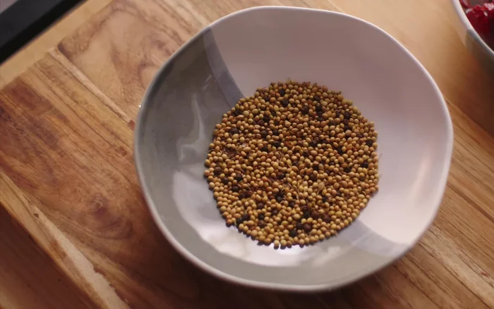 Grind the roasted spices, soaked chilies, cashew nuts, garlic, tamarind, jaggery, and a little water into a fine paste.