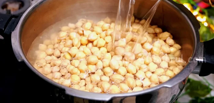 Pressure cook chickpeas with bay leaf, black cardamom, cinnamon, and salt. Add oil/ghee on top. Cook until 3-4 whistles after the first whistle on high flame, then lower the heat.