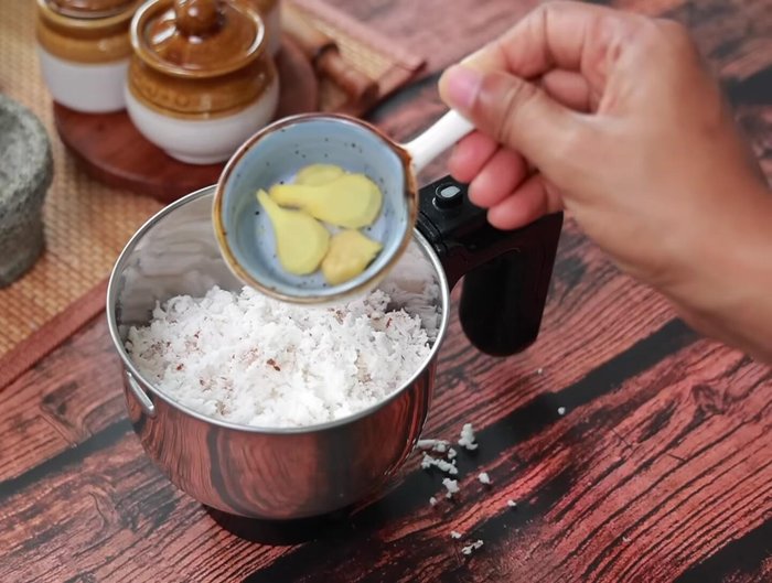 Add grated coconut, chopped ginger, green chilies, tamarind, roasted peanuts, salt, and water to a mixie jar.