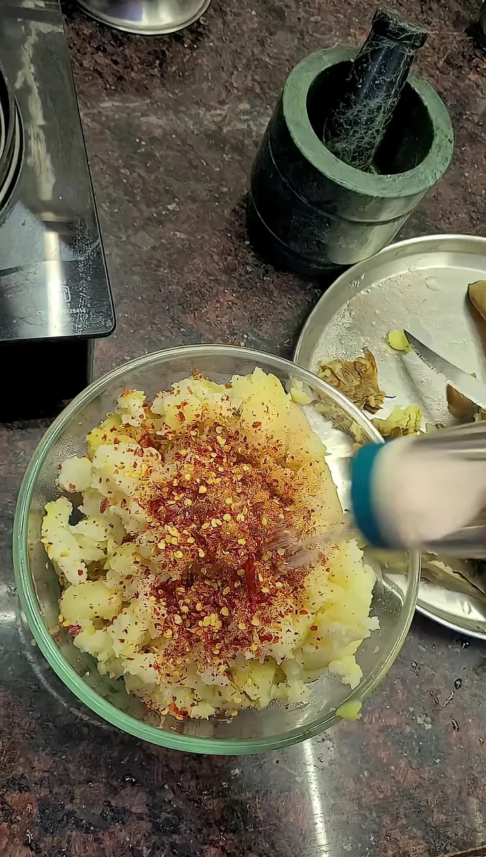 Add salt, red chili powder, coriander powder, green chilies, and optional coriander and onions to the mashed mixture.