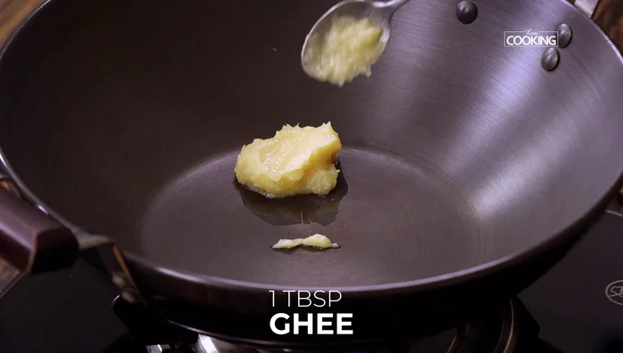 For tempering, heat ghee in a karai (109.6). Add chana dal, urad dal, mustard seeds, and cumin seeds. Let them sizzle and turn golden (113.759).
