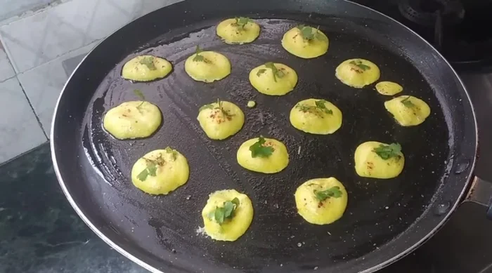 Cook the pancakes on low flame, sprinkling chilli powder and green coriander on top.