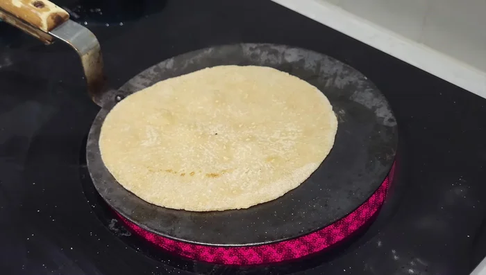 Flip the roti. Cook the other side until you start seeing brown patches appear. (Note: Do not flip too early; let it cook sufficiently to puff up properly.)