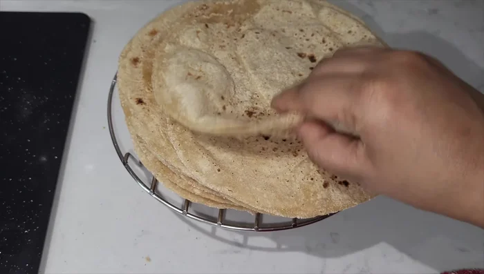 Puff up the roti by pressing gently on the surface of the roti. (Note: This helps to create air pockets, resulting in a softer roti.)
