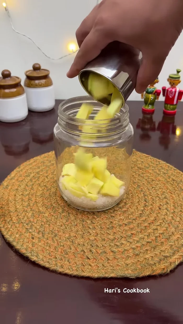 In a jar, combine half a can of semi-ripe mango pieces and four quarters of a cup of semi-ripe mango pieces. Add a pinch of turmeric and mix until the salt is coated with the mango pieces.